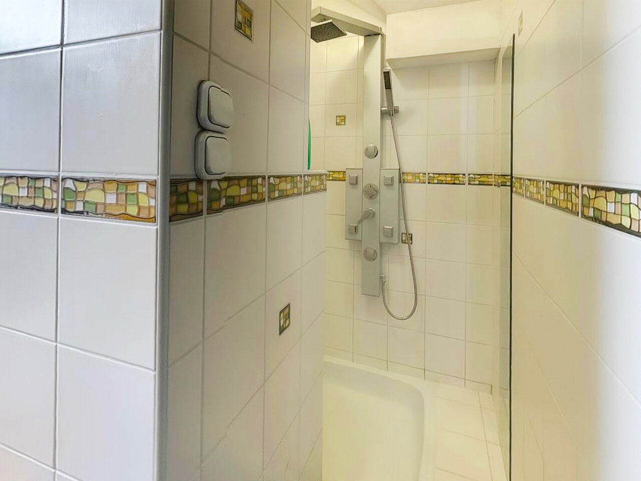 Modern zuhanykabin zuhanypanellel és üvegfallal a felújított fürdőszobában
